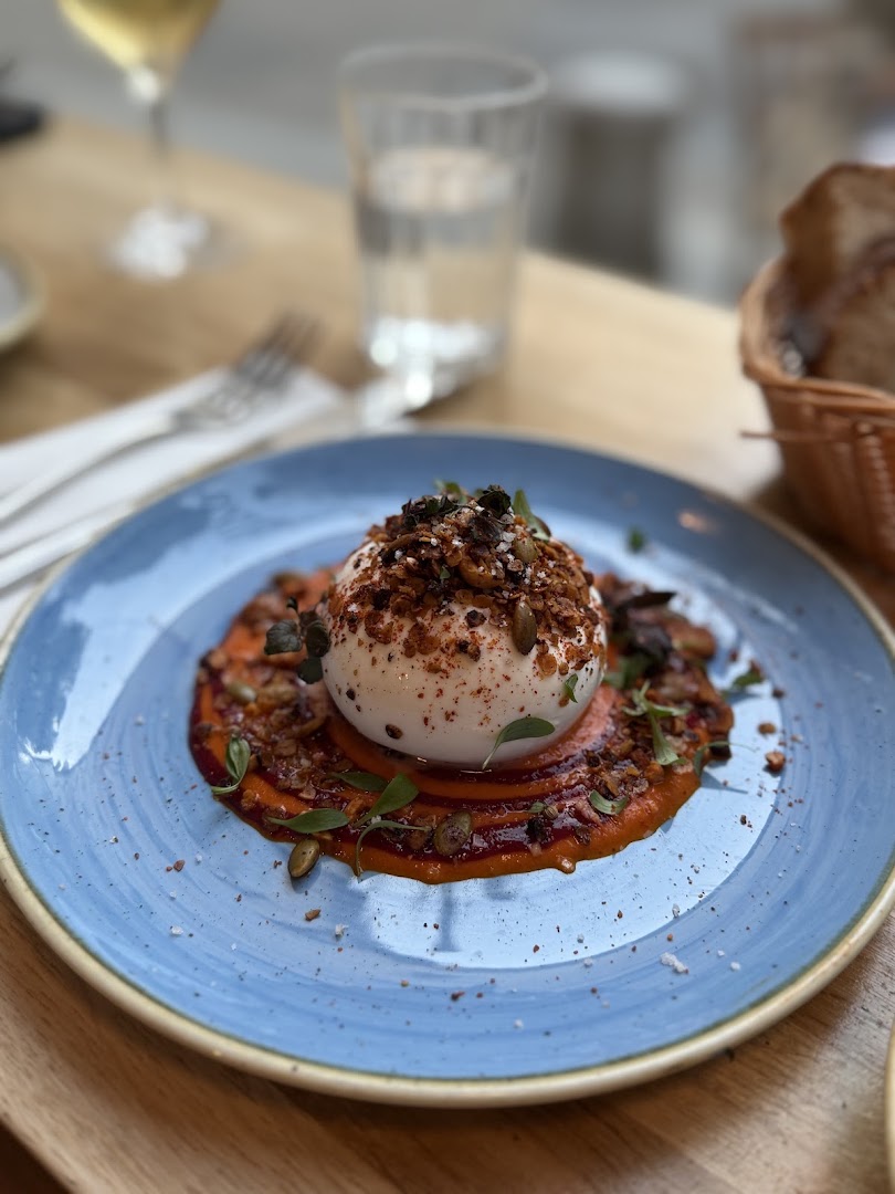 Un fromage frais servi sur une assiette bleue avec une sauce rouge